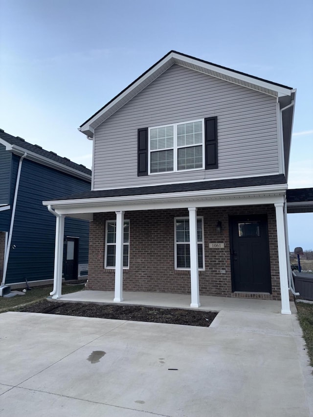 traditional-style house featuring covered porch and brick siding