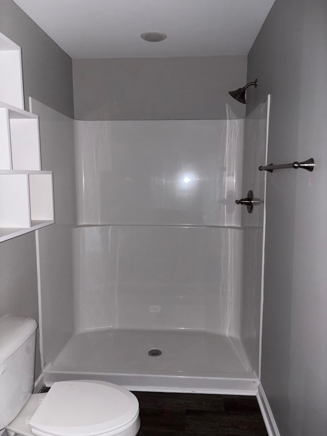 bathroom featuring a shower, toilet, and wood finished floors