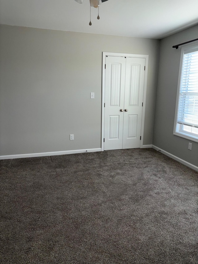 unfurnished bedroom with a closet, carpet, a ceiling fan, and baseboards