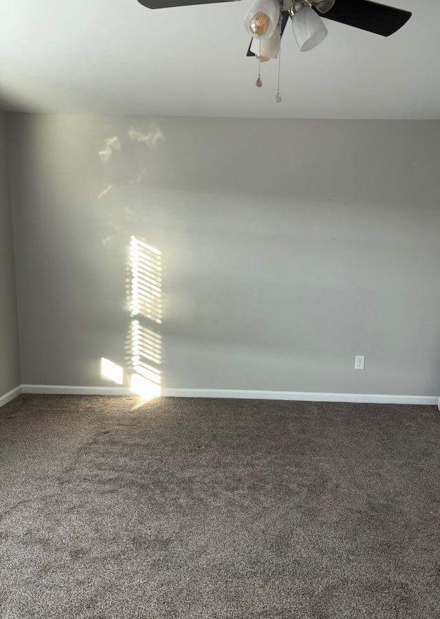 carpeted spare room featuring a ceiling fan and baseboards