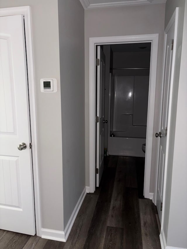 hallway featuring baseboards and dark wood-type flooring