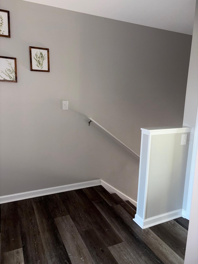 staircase featuring baseboards and wood finished floors