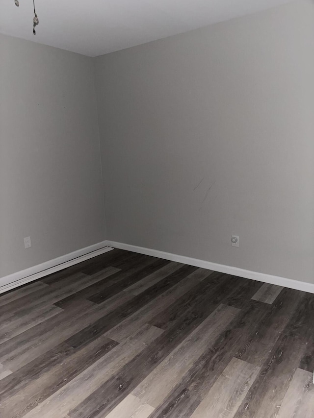 empty room with dark wood-style flooring and baseboards