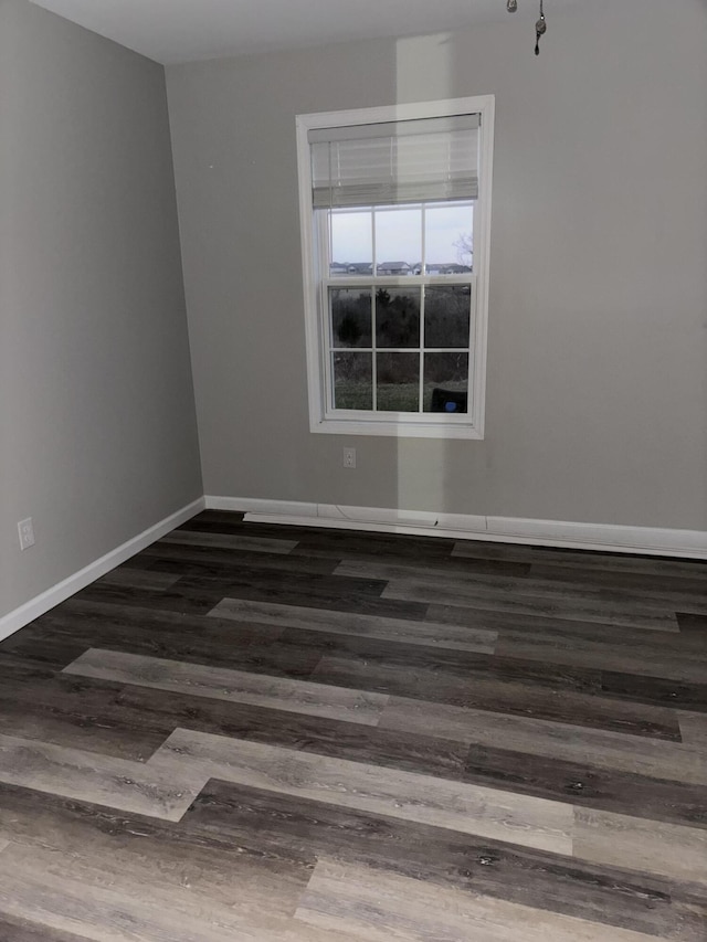 spare room with baseboards and wood finished floors