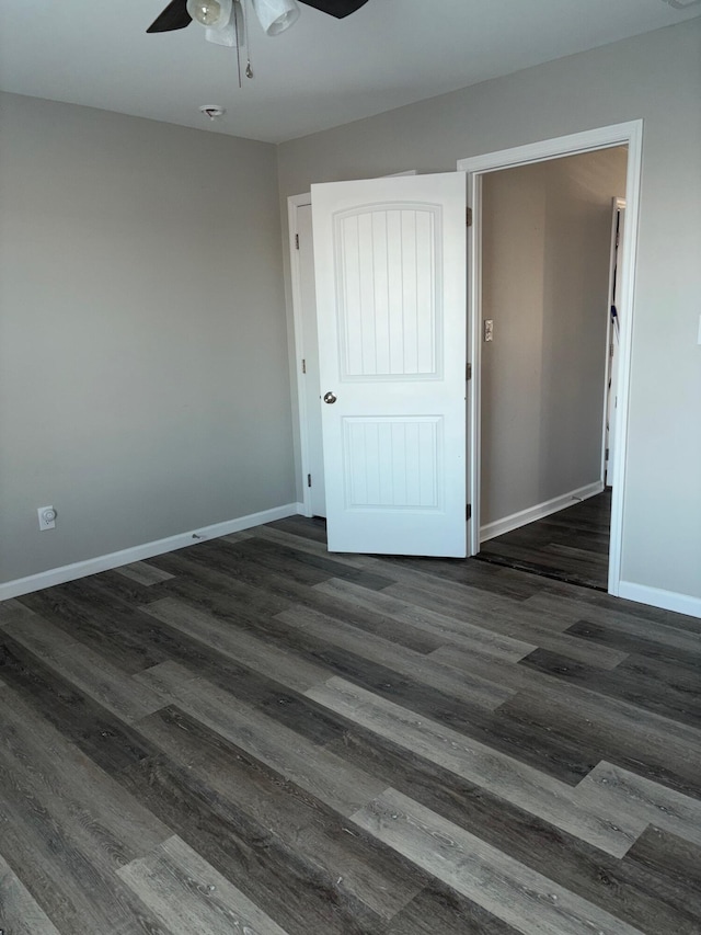 interior space featuring dark wood-style floors, a ceiling fan, and baseboards