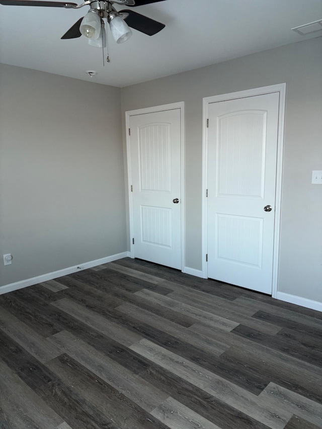 unfurnished bedroom featuring ceiling fan, dark wood finished floors, visible vents, and baseboards