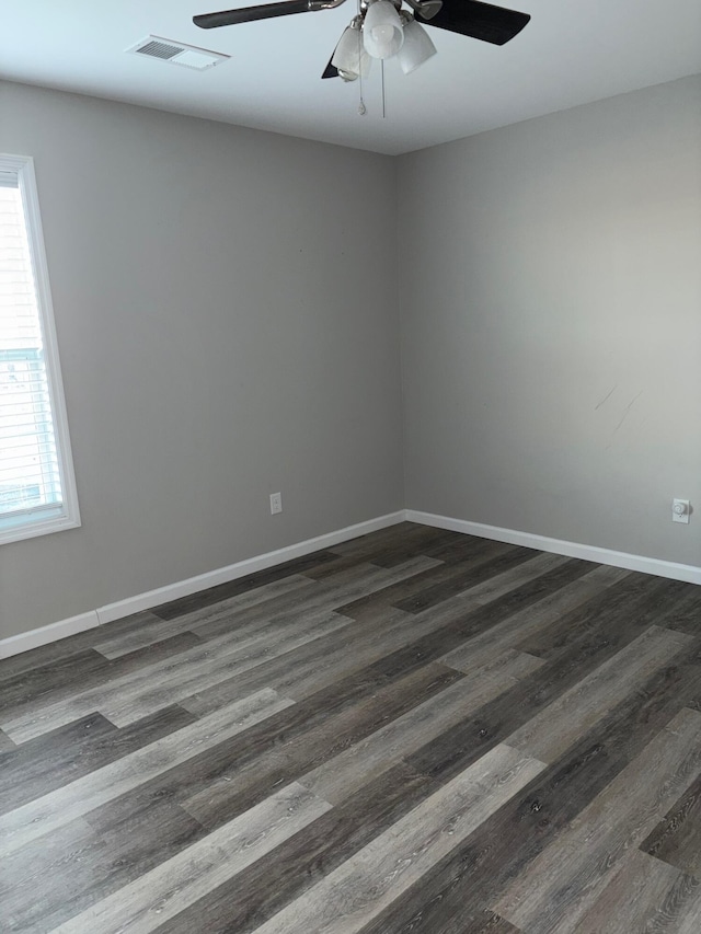 unfurnished room featuring a ceiling fan, baseboards, visible vents, and dark wood-type flooring