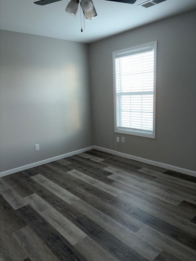 empty room featuring ceiling fan, dark wood-style flooring, and baseboards