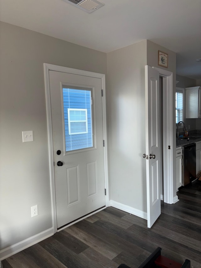 entryway with dark wood-style floors, a sink, visible vents, and baseboards