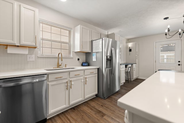 kitchen featuring white cabinets, appliances with stainless steel finishes, dark wood-style flooring, light countertops, and a sink