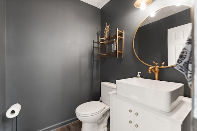 bathroom featuring toilet, baseboards, wood finished floors, and vanity