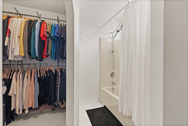 full bath featuring shower / bathtub combination with curtain, a spacious closet, baseboards, and tile patterned floors