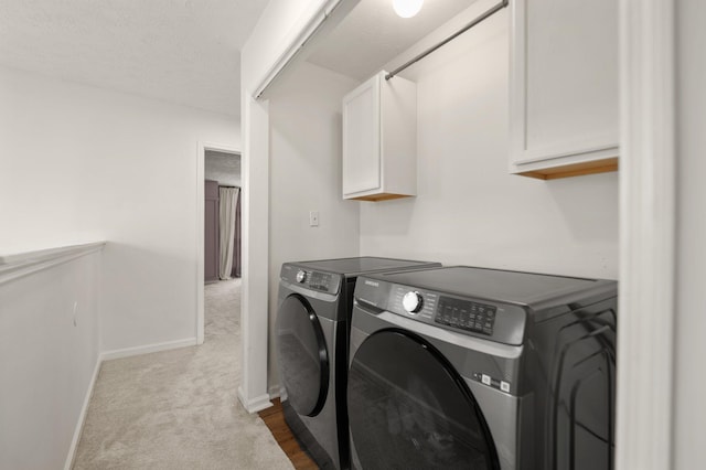 clothes washing area with a textured ceiling, separate washer and dryer, baseboards, cabinet space, and dark carpet