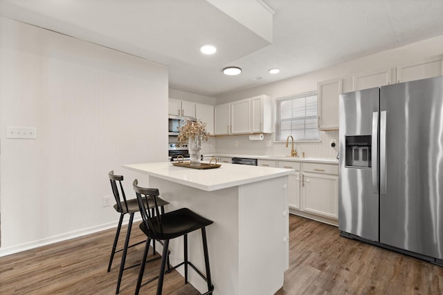 kitchen featuring stainless steel appliances, white cabinets, a sink, and a breakfast bar area