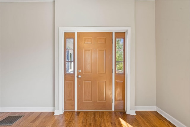 foyer entrance featuring baseboards, visible vents, and wood finished floors