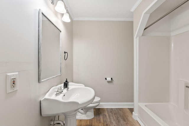 bathroom featuring baseboards, wood finished floors, toilet, and crown molding