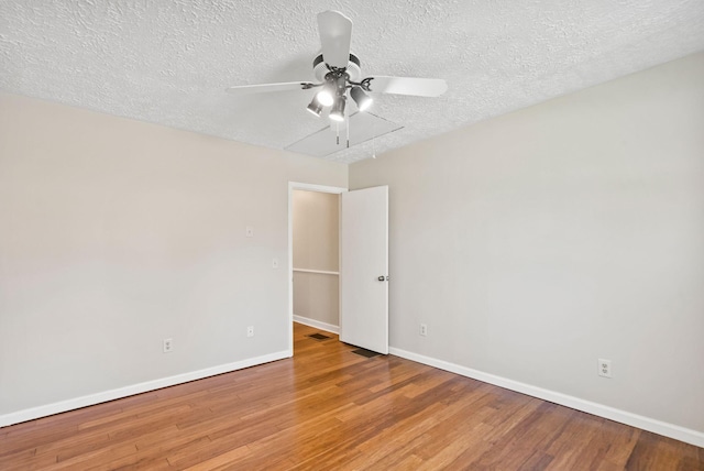 empty room featuring ceiling fan, a textured ceiling, baseboards, and wood finished floors