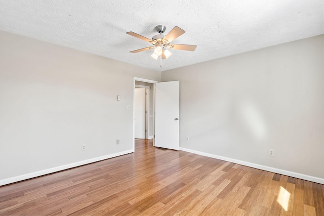 spare room with light wood-type flooring, a ceiling fan, baseboards, and a textured ceiling