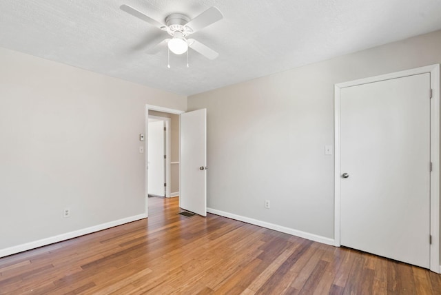 spare room featuring hardwood / wood-style flooring, ceiling fan, baseboards, and a textured ceiling