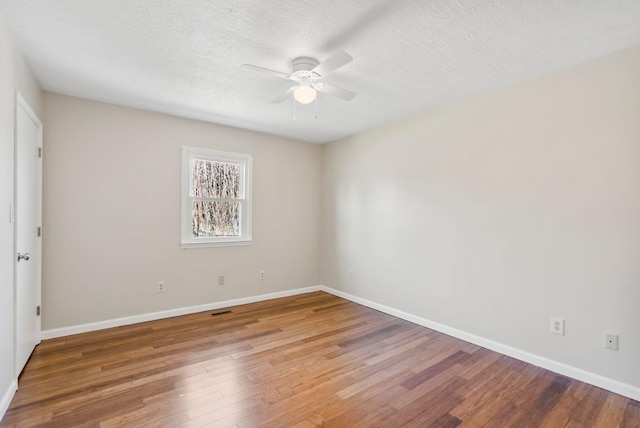 unfurnished room with a textured ceiling, ceiling fan, wood finished floors, and baseboards