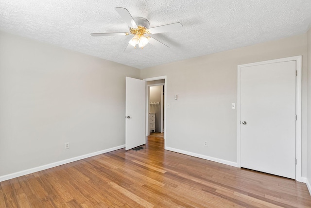 empty room featuring a ceiling fan, baseboards, a textured ceiling, and light wood finished floors