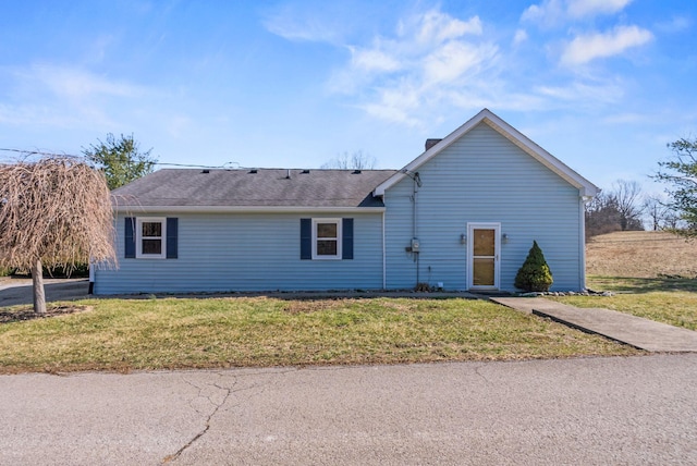 view of front facade with roof with shingles and a front yard