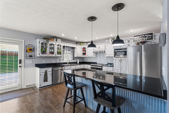 kitchen featuring dark wood-style flooring, dark countertops, appliances with stainless steel finishes, a sink, and a textured ceiling