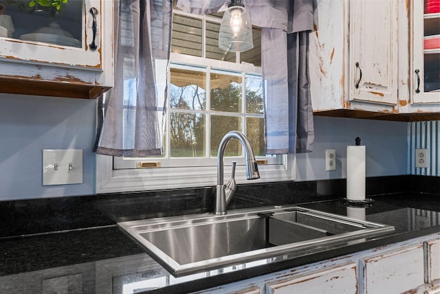 kitchen with dark countertops, glass insert cabinets, white cabinets, and a sink