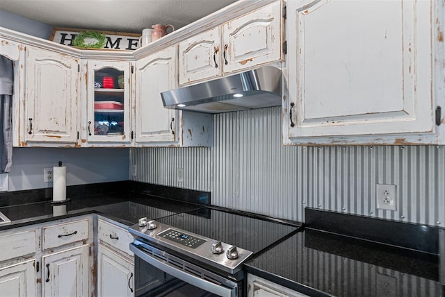 kitchen with dark countertops, under cabinet range hood, and stainless steel electric range oven