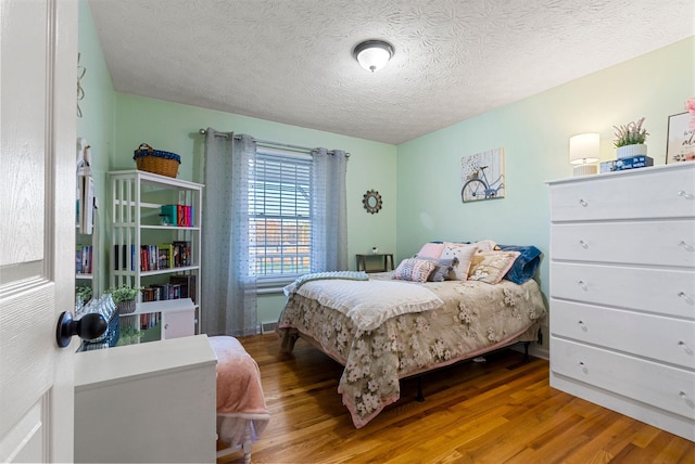 bedroom with a textured ceiling and wood finished floors