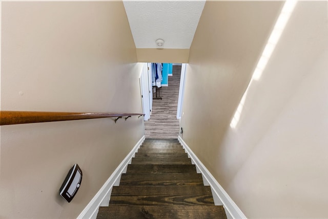 stairway with baseboards, a textured ceiling, and wood finished floors