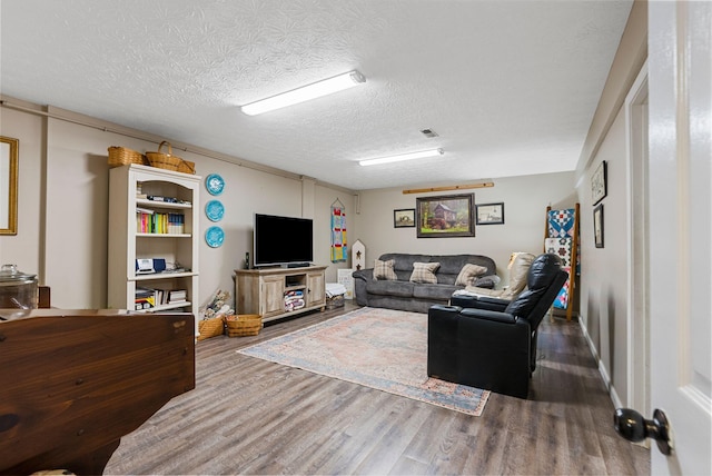 living room with a textured ceiling, visible vents, and wood finished floors