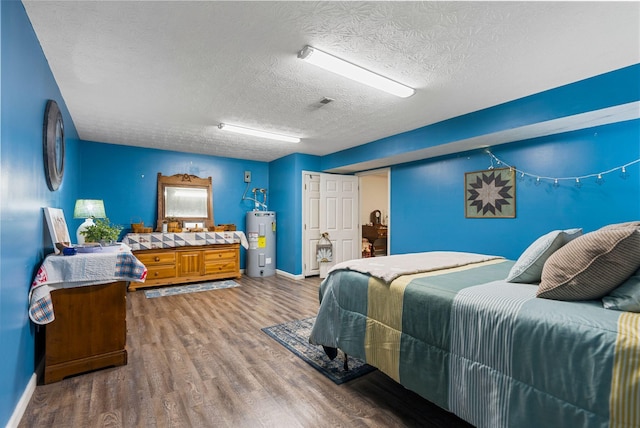 bedroom with water heater, a textured ceiling, wood finished floors, and baseboards