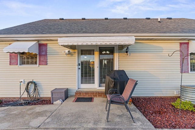 rear view of house featuring entry steps, a patio area, and a shingled roof