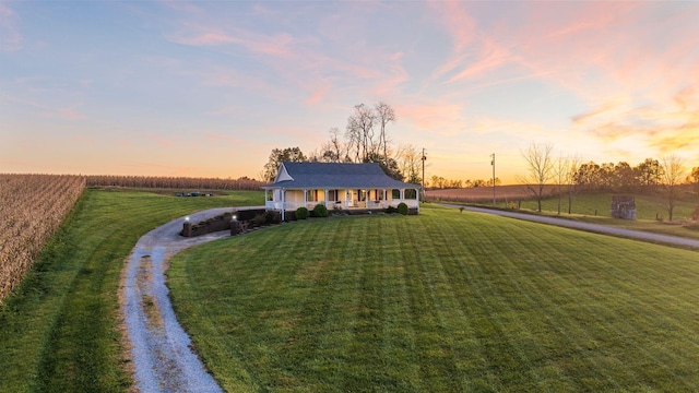 view of front of home featuring a porch, a rural view, a lawn, and driveway