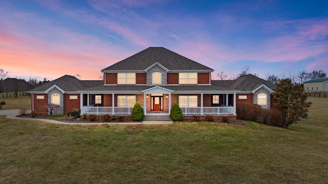 view of front of property featuring covered porch, brick siding, and a front yard