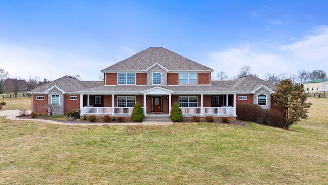 view of front of home featuring a porch, a front yard, brick siding, and fence