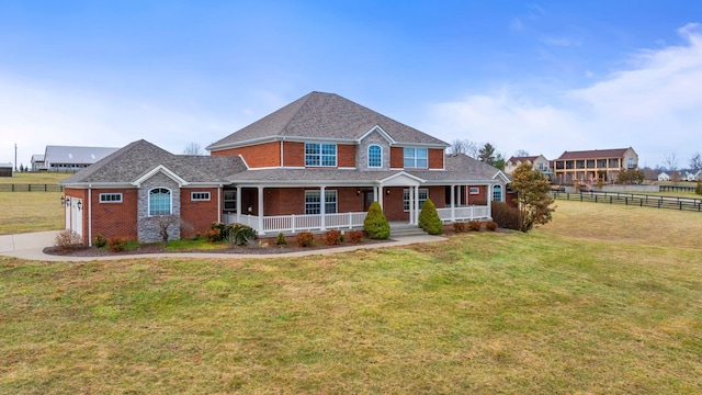 view of front facade featuring covered porch, brick siding, fence, driveway, and a front lawn