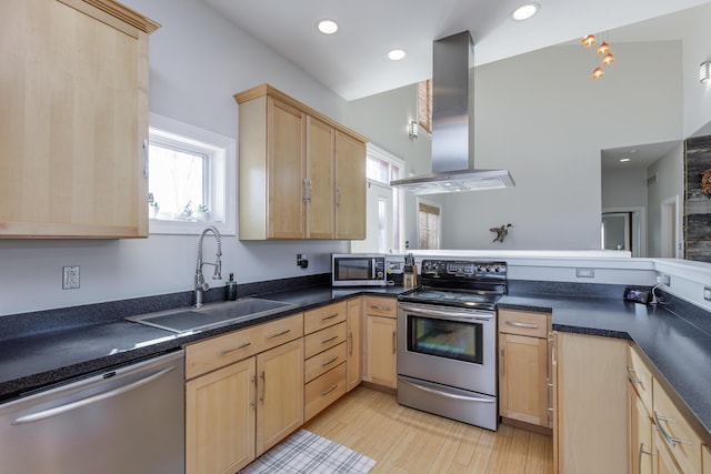 kitchen with dark countertops, appliances with stainless steel finishes, island exhaust hood, light brown cabinets, and a sink