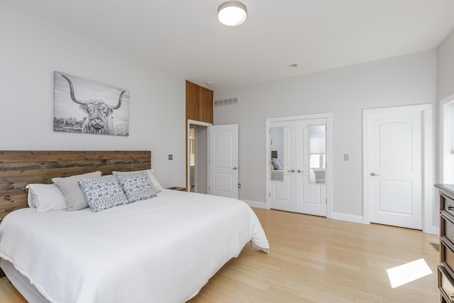 bedroom featuring visible vents, french doors, light wood-style flooring, and baseboards