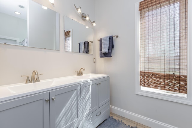 full bath with tile patterned flooring, a sink, baseboards, and double vanity