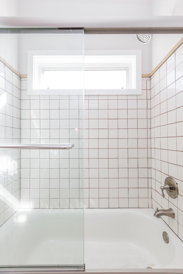 bathroom featuring enclosed tub / shower combo and a healthy amount of sunlight