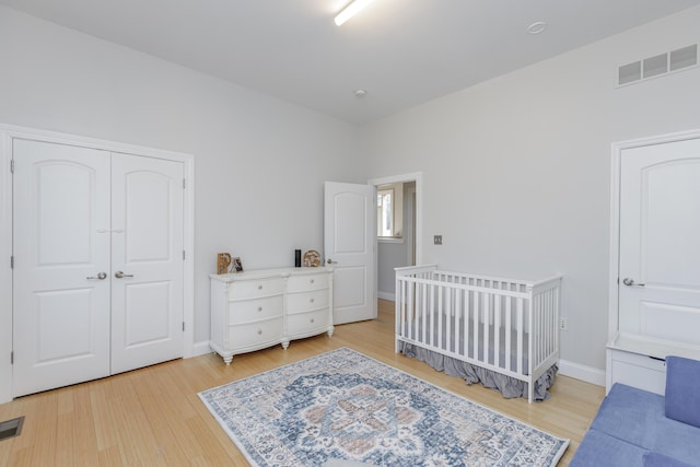 bedroom featuring a closet, baseboards, visible vents, and light wood finished floors