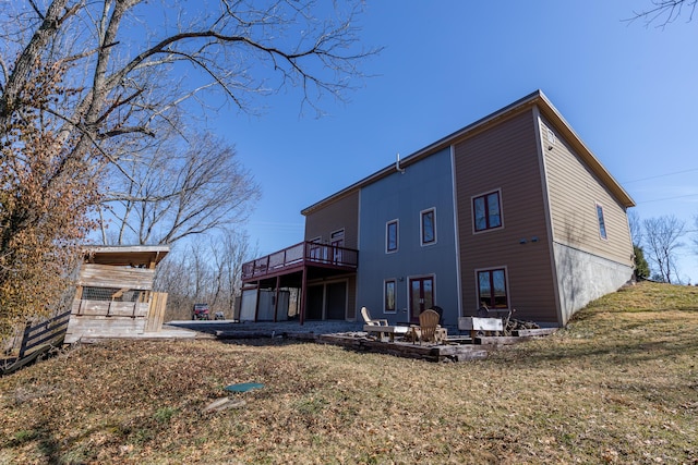 rear view of property featuring a patio area, an outdoor fire pit, a lawn, and a wooden deck