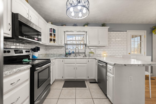 kitchen with a breakfast bar, a sink, stainless steel appliances, a peninsula, and white cabinets