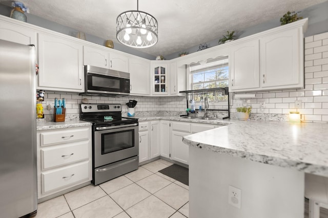 kitchen with a sink, stainless steel appliances, light tile patterned flooring, and white cabinets