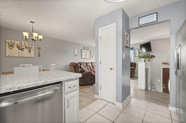 kitchen with a chandelier, stainless steel appliances, light tile patterned flooring, a textured ceiling, and white cabinetry