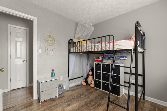 bedroom with baseboards, a textured ceiling, and wood finished floors