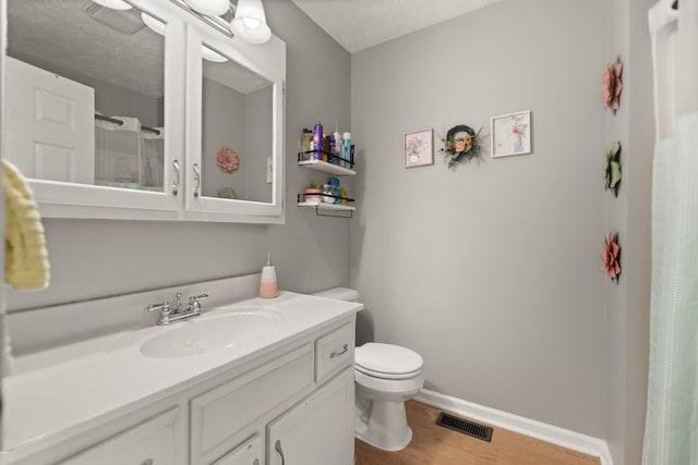 full bath with vanity, wood finished floors, visible vents, baseboards, and toilet