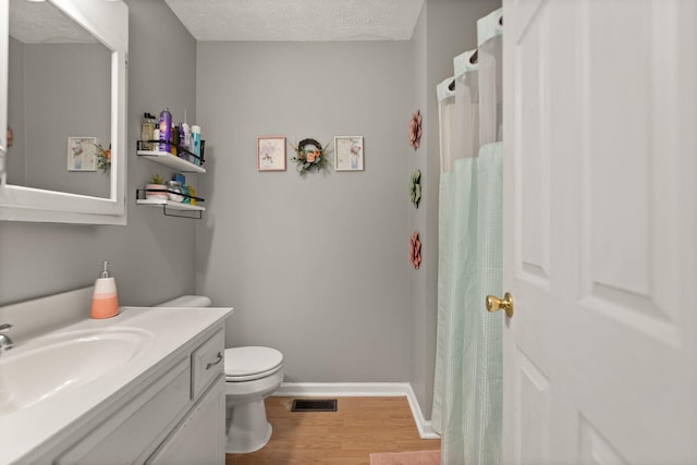 full bath with toilet, a textured ceiling, wood finished floors, baseboards, and vanity